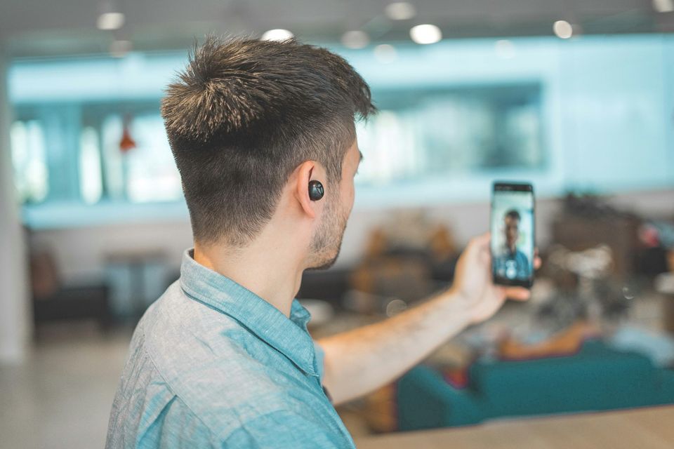 A person on a video call wearing an earpiece, illustrating remote video interpretation.