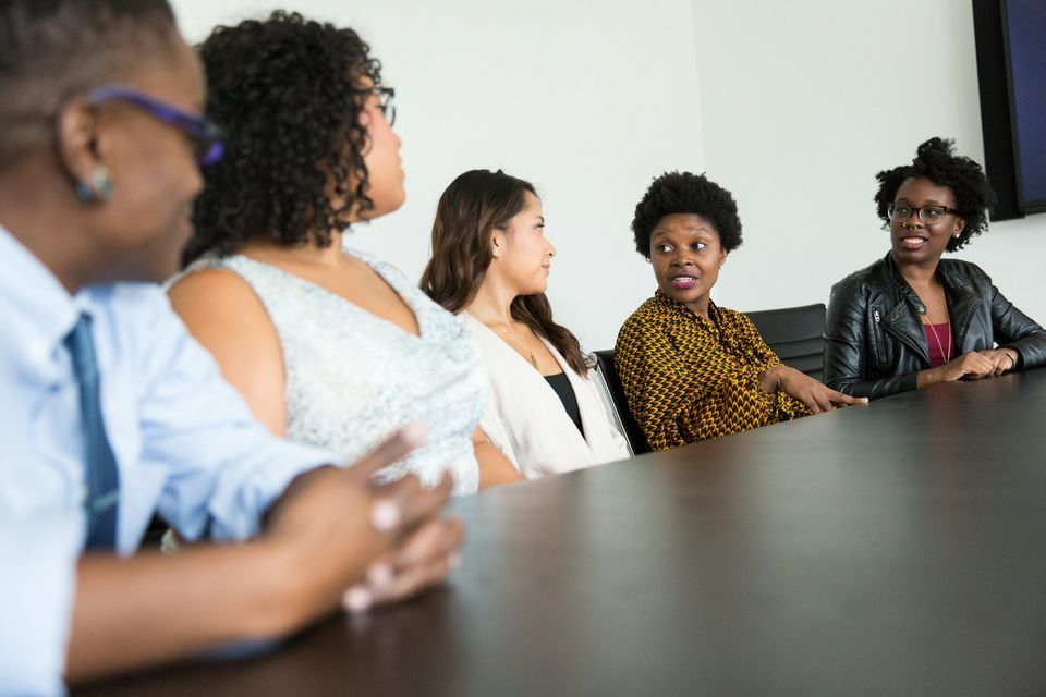 People in close conversation across a table, listening to one another — the everyday setting of interpreting work.